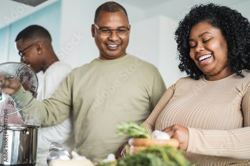 Happy black family cooking inside kitchen at home -Focus on daughter face