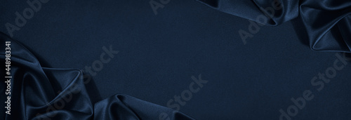 Beautiful dark blue silk satin background. Soft folds on shiny fabric. Luxury background with copy space for text, design. Web banner. Flat lay, top view.