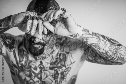Grayscale shot of a cool Caucasian man with his whole body and face covered with tattoos