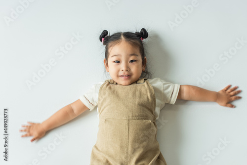 high angle view of happy asian toddler girl with outstretched hands on grey