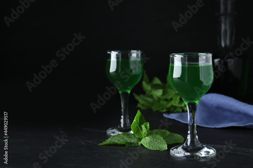 Delicious mint liqueur on black table. Space for text