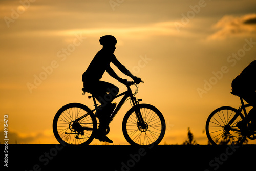 Silhouette man cycling on sunset background