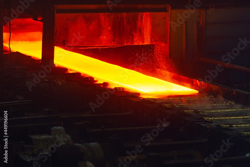Incandescent hot rolled steel sheet in soft focus on a conveyor belt. Metallurgical production, hot rolling mill shop.