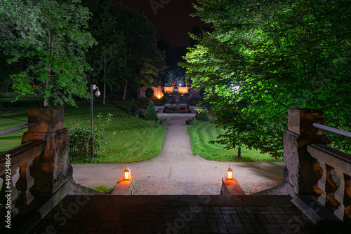 Park w mieście Iłowa w Polsce w nocnej scenerii. Ciemności rozświetlają lampiony ustawione na kamiennych schodach.