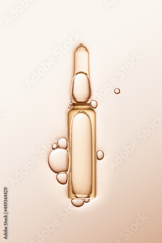 ampule with serum and bubbles around on cream-coloured background.