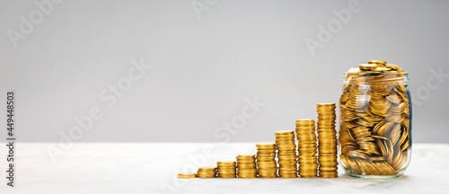 Gold coins by steps and a full glass jar of coins. Savings growth concept. Template Copy space for text