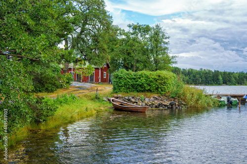 A beautiful summer day in the Turku archipelago (Finland). An old traditional red house and a rowing boat on the beach. A common view when moving around the archipelago.