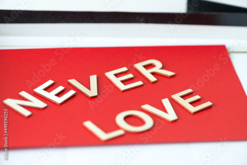 the expression "never love" in san serif capital letters on a red background - close up using a macro lens - shallow depth of field (subjective focusing)