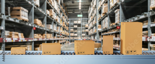 Smart warehouse management system concept.Cardboard boxes on conveyor rollers ready to be shipped by courier for distribution in warehouse.Huge distribution warehouse with high shelves and loaders.