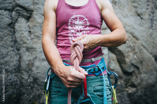 Rock climber wearing safety harness making a eight rope knot