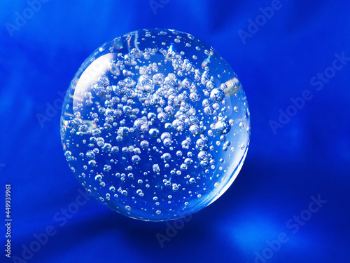 Transparent glass ball with air bubbles inside on a blue background