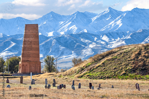 Burana tower which is an old and large minaret in the ruins of the ancient site of Balasagun with tombstones known as Balbas in the foreground, Kyrgyz