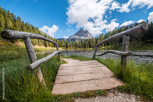 Wooden bridge wide angle photo on Italian Lago d'Antorno or Antorno Lake with stunning Tre Cime di Lavaredo 2999m peaks on the background in Belluno province, northern Italy.