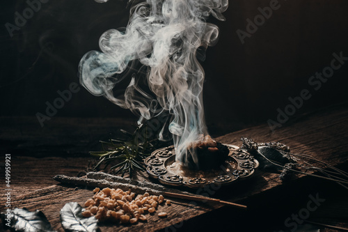 Charcoal burning with incense, incense resin, rosemary, laurel, lavender on a rustic wooden table, smudge stick, smudging, energetic cleansing and smoking.Sahumar 
