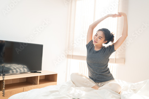 Bedroom concept in the morning the pretty girl just waking up and stretching her body on the brown wooden bed