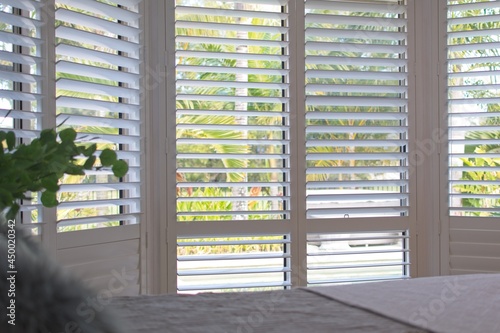 Luxury white indoor plantation shutters in bedroom - selective focus