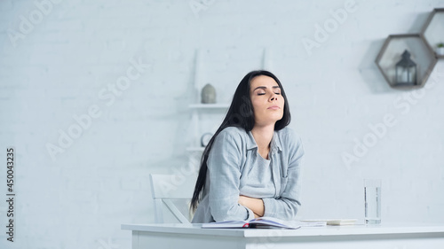 worried woman with closed eyes breathing while sitting at desk in office