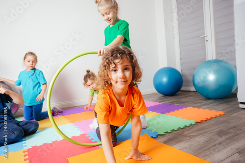 Curly girl crawling on colorful floor through hula hoops