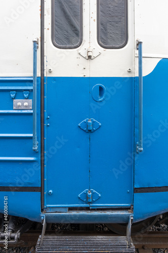 Closeup of a vintage train car door with a step and two knobs.