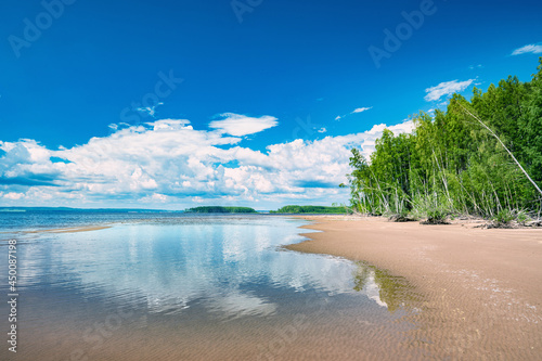 Summer landscape sandy beach, white clouds in the blue sky.