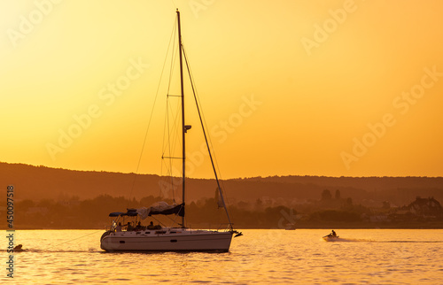 Silhouette of yacht at sunset moving on calm lake