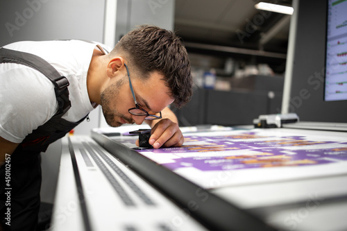 Worker checking print quality of graphics in modern printing house.