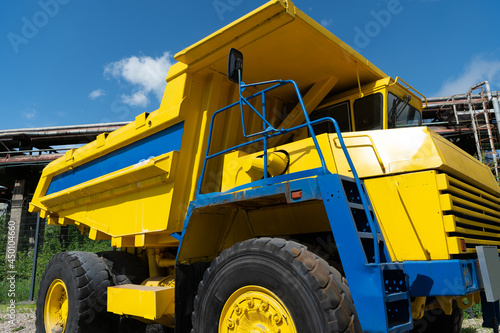 Heavy yellow dump truck for transporting iron ore and coking coal at a metallurgical plant on a bright sunny day
