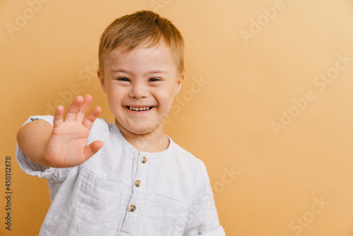 White boy with down syndrome smiling and gesturing at camera