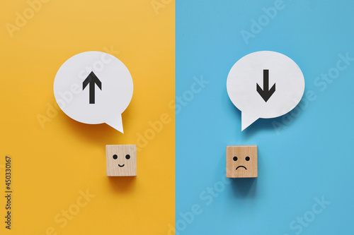 Wooden cubes with an image of an up arrow and a down arrow above them. The choice between progressive and passive thinking