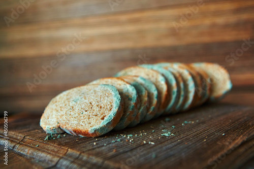 Moldy spoiled bread on a wooden background. Improper storage of food.
