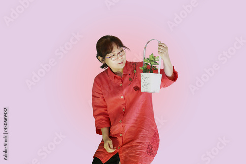 붉은색 옷을 입은 한국의 평범한 50대 주부가 작은 꽃이 핀 꽃 바구니를 들고 있는 모습입니다. 
