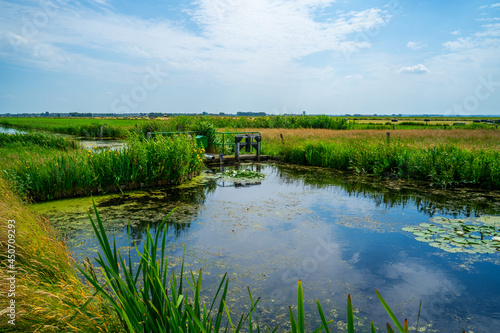 Panoramic polder landscape with a pond and a weir 