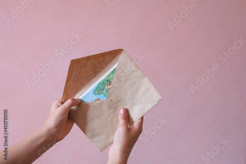 The child holds a paper envelope in his hand. letter for christmas. Letter to Santa Claus. Postal service. The girl wants to send or receive a letter. People communication concept. Christmas creative