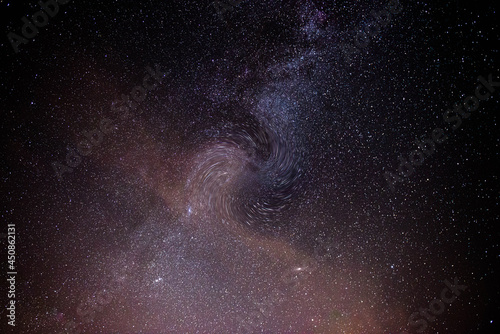 Fotografia nocnego nieba, ilustrująca obecność i działanie czarnej dziury na pobliską galaktykę.
