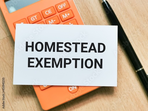 Phrase homestead exemption on white card with calculator and a pen.