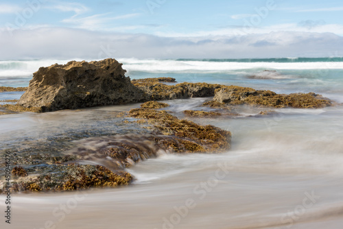 The tide flowing in over rocks at the beach