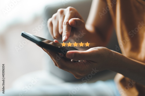 Close up of woman customer giving a five star rating on smartphone. Review, Service rating, satisfaction, Customer service experience and satisfaction survey concept..