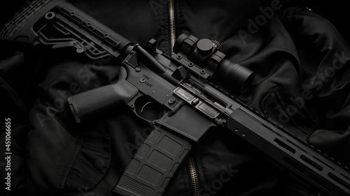 Modern automatic rifle with a telescopic sight on a dark back. The uniform of a guard or a mercenary.