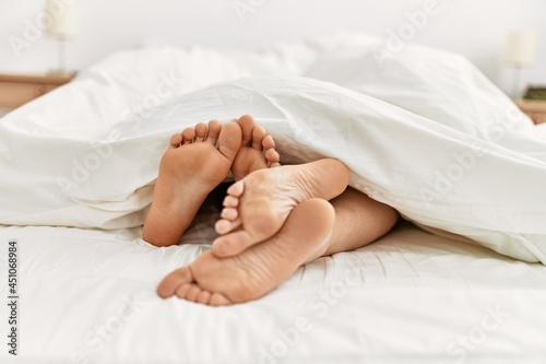 Couple feet under sheets on the bed at home.