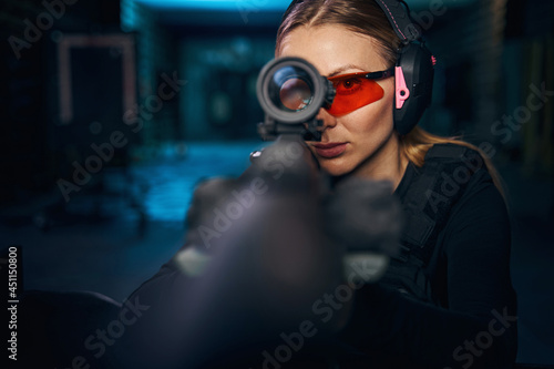 Serious woman using a telescopic sight mounted on the weapon