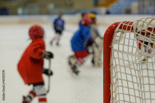 Children playing ice hockey in arena. Young hockey players practising.