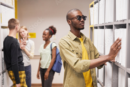 Portrait of blind African-American man choosing book in library