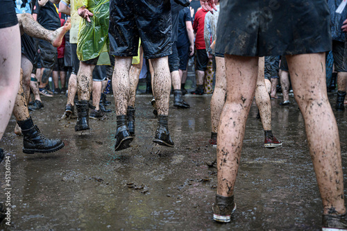 Dirty legs of people dancing in the mud during concert.