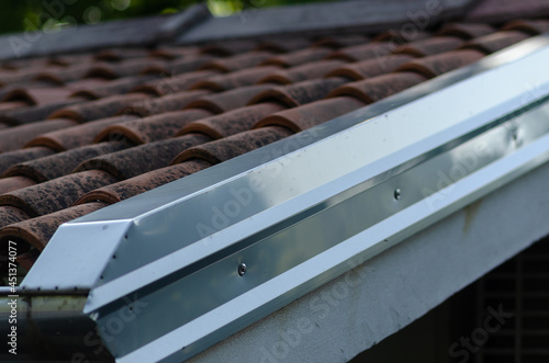 Building: cornice with galvanized steel sheet, detail of the house on the part of the double-sided roof with ridge tiles. roof flashing,