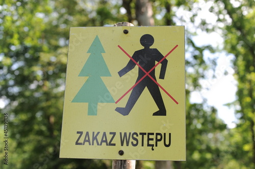 Information sign in Polish “Zakaz wstępu”, English translation “No entry” or “No trespassing” with icons of a person and a tree forbidding an entry to the forest