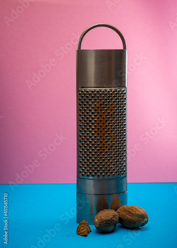 nutmeg grater on a pink and blue background cooking concept , spices .