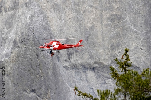Versam, Switzerland, 04 10 2021, Helicopter of Swiss rescue system flying over Ruinaulta ravine or gorge, performing a rescue action. On the background there is a rocky wall.