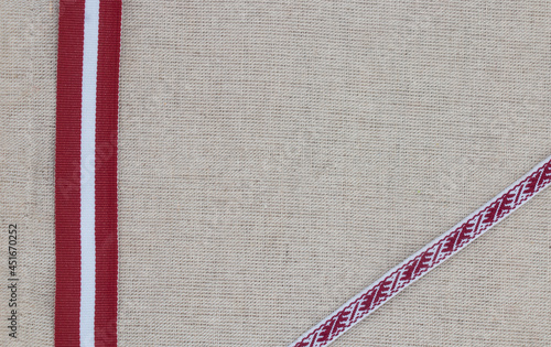 Composition of national latvian patterned ribbon and flag on linen fabric