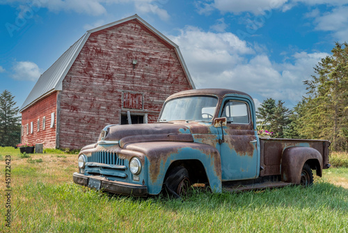 Vintage red barn with abandoned truck in a farmyard on the prairies in Saskatchewan