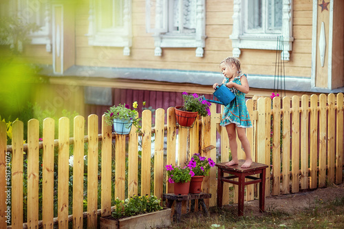 girl watering flowers, petunia, garden, young florist, summer in the village, joy, happiness, children, front garden, new wooden fence